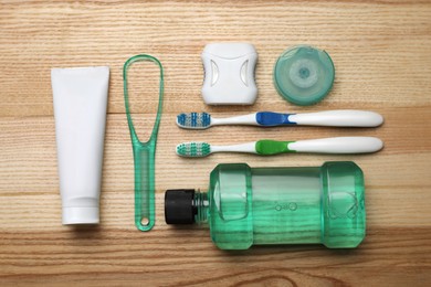 Flat lay composition with tongue cleaner and teeth care products on wooden table