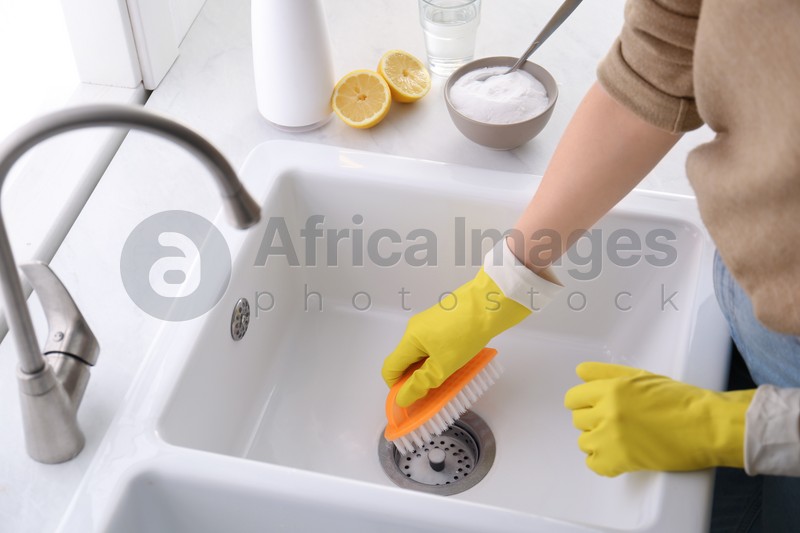 Photo of Woman using baking soda and brush to clean sink, closeup