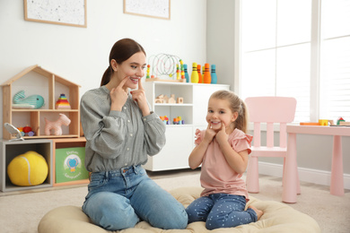 Speech therapist working with little girl in office