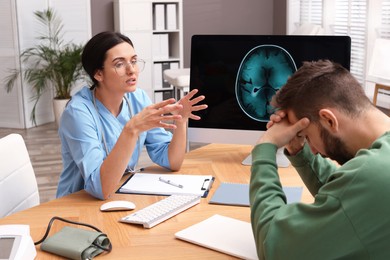 Neurologist consulting patient at table in clinic
