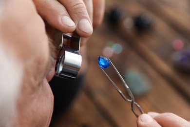 Male jeweler evaluating precious gemstone in workshop, closeup
