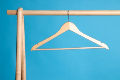 Empty clothes hanger on wooden rack against light blue background