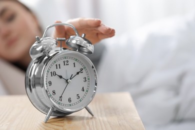 Photo of Young woman turning off alarm clock at home in morning, closeup. Space for text