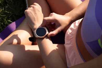Woman checking fitness tracker after training outdoors, closeup