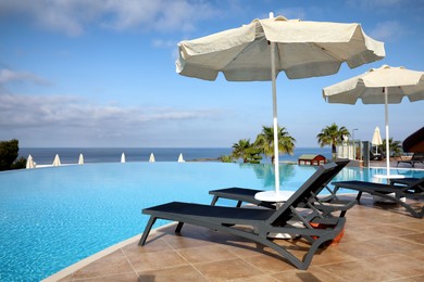 Chaise longues and beach parasols near infinity pool at resort