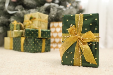 Beautiful Christmas gift and blurred pile of presents on background. Space for text
