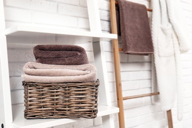 Basket with clean towels on shelf near brick wall. Space for text