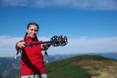 Hiker with trekking poles in mountains, focus on tips