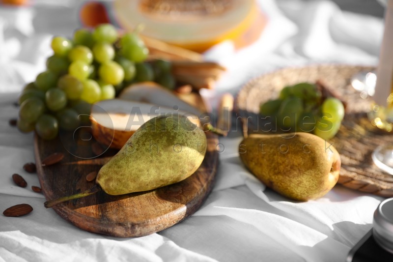 Photo of Delicious pears and grapes on picnic blanket, closeup