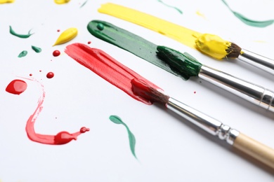 Brushes with different paints and strokes on white background, closeup