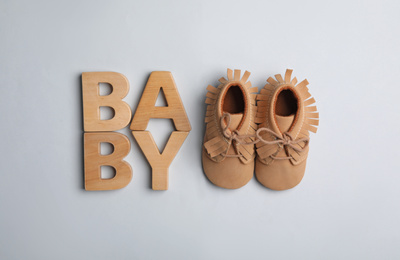 Flat lay composition with child's booties and word Baby on light background
