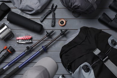 Photo of Flat lay composition with trekking poles and other hiking equipment on grey wooden background