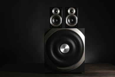 Modern powerful audio speaker system on table against black background