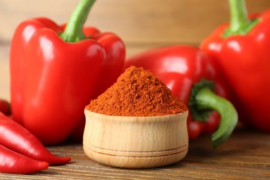 Paprika powder and fresh chili peppers on wooden table, closeup