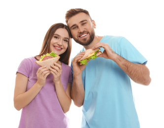 Young couple with tasty sandwiches on white background