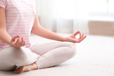Young woman meditating on floor at home, closeup. Zen concept