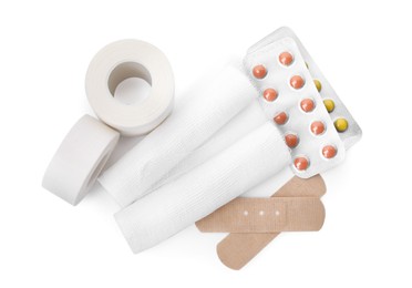Bandage rolls and medical supplies on white background, top view