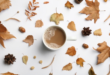 Photo of Cup of hot drink and autumn leaves on white background, flat lay. Cozy atmosphere