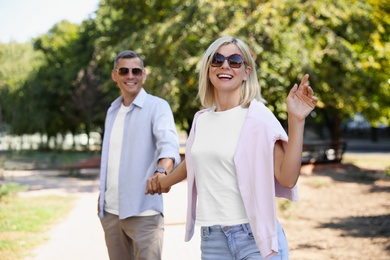 Photo of Happy couple walking along park on summer day