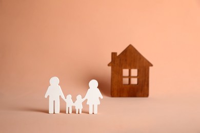 Figures of family and house on pink background