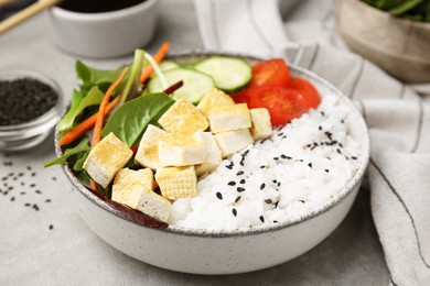 Photo of Delicious poke bowl with vegetables, tofu and mesclun on light grey table, closeup