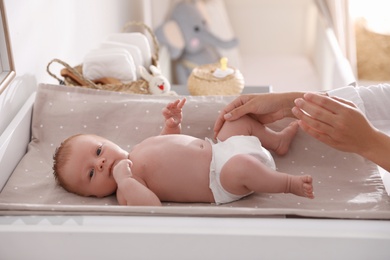 Photo of Mother changing her baby's diaper on table in room