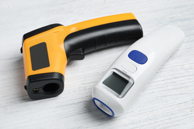 Modern non-contact infrared thermometers on white wooden background