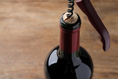 Photo of Opening wine bottle with corkscrew on table, closeup. Space for text