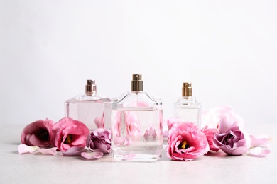 Bottles of perfume and beautiful flowers on light table