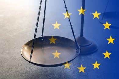 Double exposure of European union flag and scales of justice on grey table, closeup