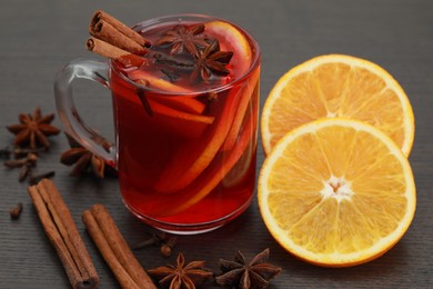 Photo of Aromatic punch drink and ingredients on wooden table, closeup