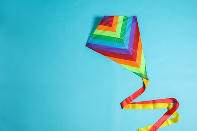 Bright rainbow kite on light blue background, top view. Space for text