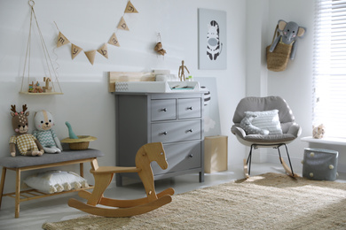Beautiful baby room interior with toys, rocking chair and modern changing table