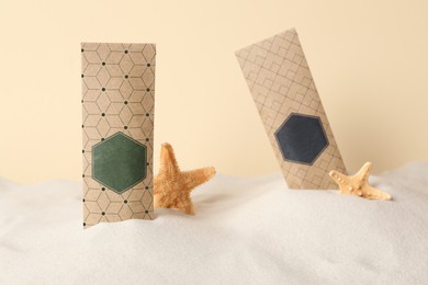 Scented sachets and starfishes in sand against beige background