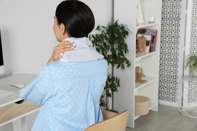 Photo of Woman using heating pad on neck at home