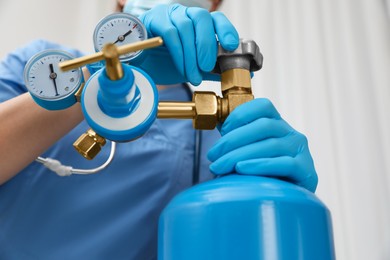 Medical worker checking oxygen tank in hospital room, closeup