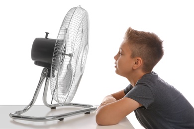 Little boy enjoying air flow from fan on white background. Summer heat