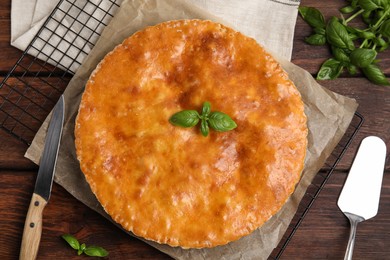 Delicious pie with meat and basil on wooden table, flat lay