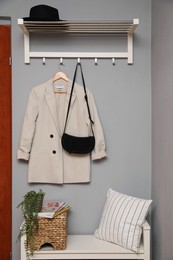 Bench and coat rack on grey wall in hallway. Interior element