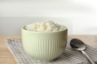 Bowl with tasty cooked rice on wooden table, closeup