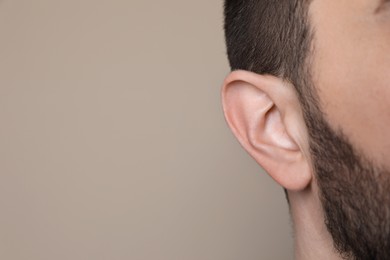 Man on grey background, closeup of ear. Space for text
