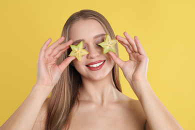 Young woman with cut carambola on yellow background. Vitamin rich food