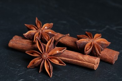 Aromatic anise stars and cinnamon sticks on black table