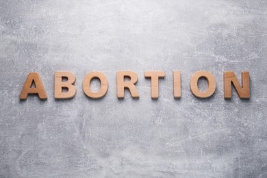 Word Abortion made of wooden letters on grey background, flat lay