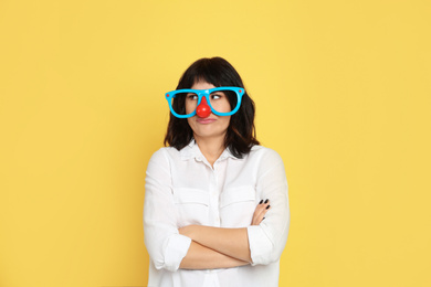 Emotional woman with funny glasses on yellow background. April fool's day