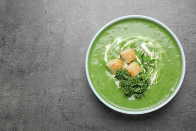 Tasty kale soup with croutons on grey table, top view. Space for text