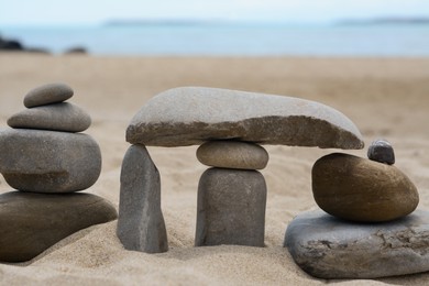 Photo of Stacks of stones on beautiful sandy beach near sea, closeup