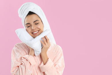 Young woman wiping face with towel on pink background. Space for text