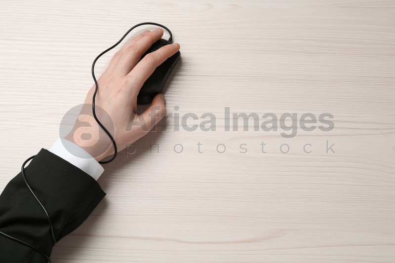 Internet addiction. Top view of man using computer mouse at wooden table, hand tied to device with cable