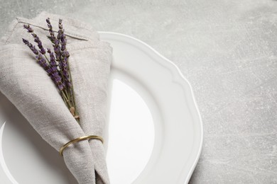 Plate with fabric napkin, decorative ring and lavender on gray background, space for text
